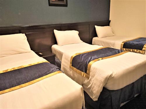 three beds in a room with white and yellow sheets at Al Barakah Mawaddah Hotel in Makkah