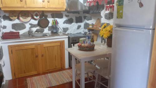 a kitchen with a small table and a refrigerator at Adega do Pesqueiro Alto in Lajes do Pico