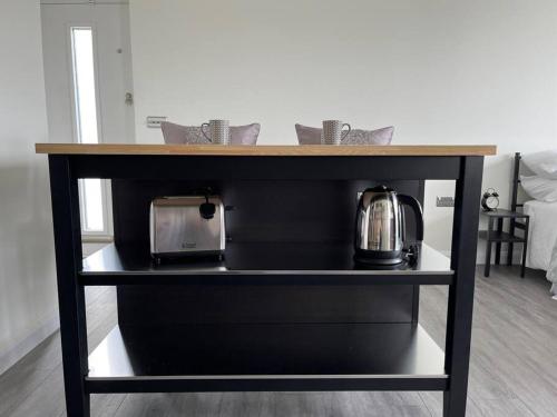 a counter with a microwave and a tea kettle on a shelf at Studio apartment in Harefield in Harefield