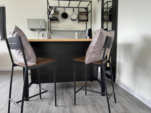 a kitchen with two bar chairs and a counter at Studio apartment in Harefield in Harefield