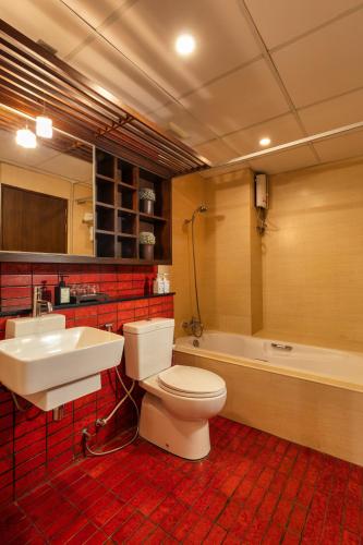 a bathroom with a toilet and a sink and a tub at The Grand Napat in Chiang Mai