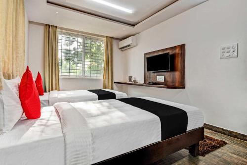 a hotel room with two beds and a television at Collection O 73565 J J Global Exotics Stays in Bangalore