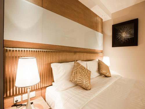a bedroom with a white bed with a wooden headboard at Garden Sentral Hotel in Kuala Belait