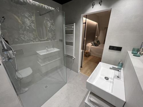y baño blanco con lavabo y ducha. en Hi! Burgos - SIDI - VUT-472 - Exclusivo apartamento moderno en el corazón de la ciudad, en Burgos