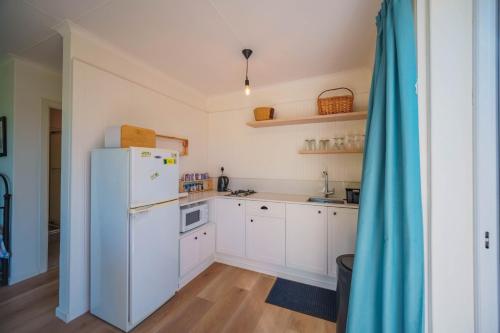 a kitchen with white cabinets and a refrigerator at Seester Strandhuis in Jeffreys Bay