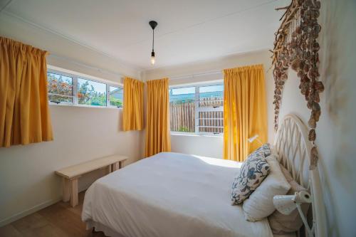 a bedroom with a bed and a window with yellow curtains at Seester Strandhuis in Jeffreys Bay