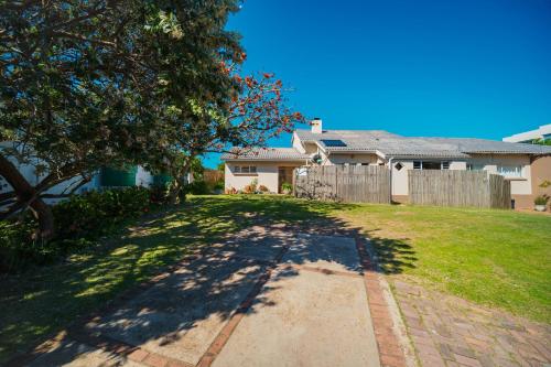 a house with a tree and a fence at Seester Strandhuis in Jeffreys Bay