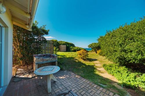 a bench sitting on a brick patio next to a house at Seester Strandhuis in Jeffreys Bay