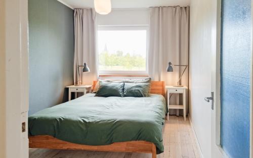 Schlafzimmer mit einem Bett mit grüner Bettwäsche und einem Fenster in der Unterkunft Cozy apartment in Suuremõisa in Suuremõisa