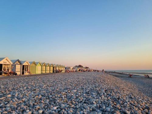 a beach covered in lots of rocks and beach huts at La Masure - Jacuzzi privatif - La mer à deux pas in Cayeux-sur-Mer