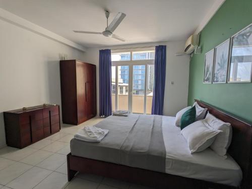 ein Schlafzimmer mit einem großen Bett und einem großen Fenster in der Unterkunft Palmyrah Residencies in Colombo