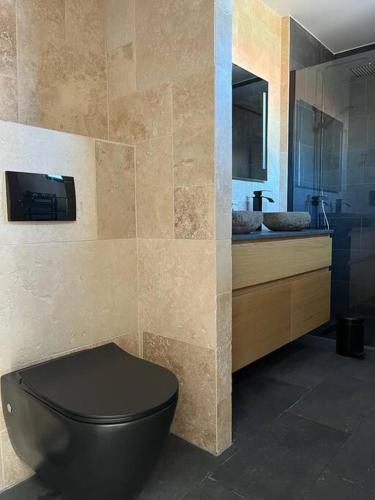 a bathroom with a black toilet and a sink at La Masure - Jacuzzi privatif - La mer à deux pas in Cayeux-sur-Mer
