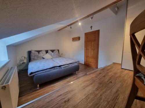 een slaapkamer met een bed en een houten vloer bij Ferienwohnung Gschwendt 