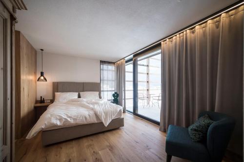 a bedroom with a bed and a chair and a window at OVINA`s HAUS in Sand in Taufers