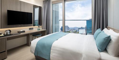 a hotel room with a bed and a desk with a television at Utop Boutique Hotel&Residence in Gwangju