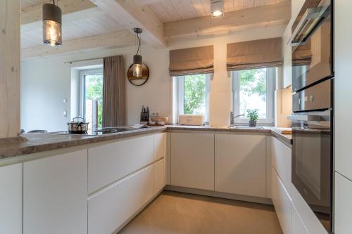 a kitchen with white cabinets and windows at Lodge54 in Sankt Peter-Ording