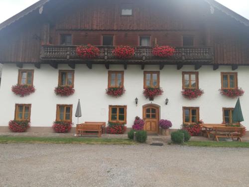 un bâtiment blanc avec des fleurs et des bancs devant lui dans l'établissement Eisl, à Gmunden