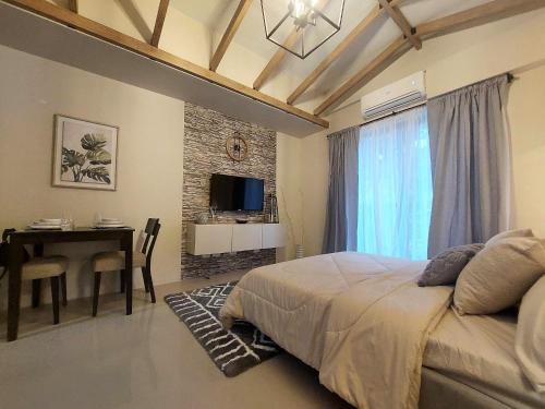 a bedroom with a bed and a table and a television at Alpine Breeze at Crosswinds Tagaytay in Tagaytay