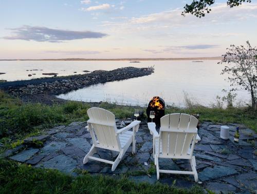 two chairs and a fire pit next to the water at Lucky Bay Hideaway - Seaview Sauna & cedar hot tub in Campbellton