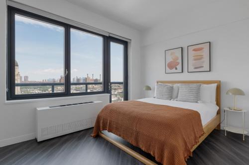 ein weißes Schlafzimmer mit einem Bett und großen Fenstern in der Unterkunft East Village 1br w balcony garden gym nr bars NYC-1211 in New York