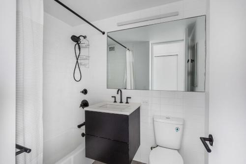 ein Badezimmer mit einem Waschbecken, einem Spiegel und einem WC in der Unterkunft East Village 1br w balcony garden gym nr bars NYC-1211 in New York