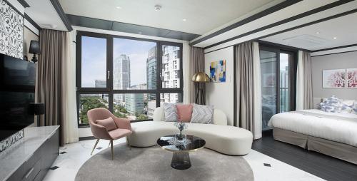 a bedroom with a white couch and a bed and a window at Utop Boutique Hotel&Residence in Gwangju