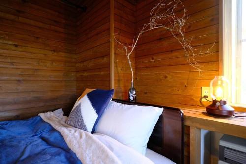 um quarto com uma cama e uma parede de madeira em ヒウチバコ em Fujikawaguchiko
