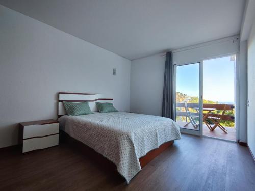 a bedroom with a bed and a large window at Machico Terrace in Machico