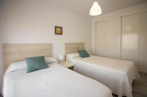 two beds in a room with white and green at White dreams next to the sea in Algarrobo-Costa