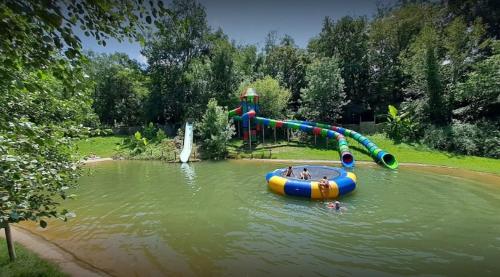 a water slide in a pond with a playground at Camping le Moulin de David -Gaugeac Monpazier 24540 - Cabane -Mobil-home 3 et 2 chambres in Gaugeac