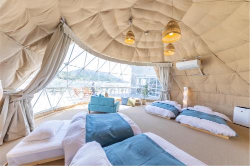 a room with three beds in a tent at GLAMP VILLAGE SETOUCHI-SHIMANAMI in Onomichi