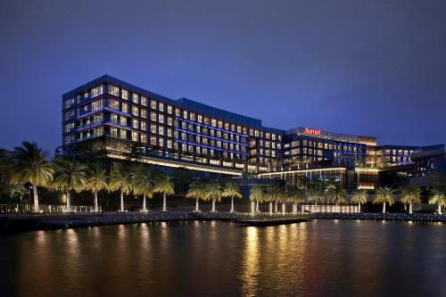 a building with palm trees in front of a body of water at The OCT Harbour, Shenzhen - Marriott Executive Apartments in Shenzhen
