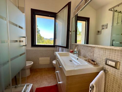 a bathroom with a sink and a toilet and a window at Villa Lotty a 5 minuti a piedi dal mare in Torre delle Stelle