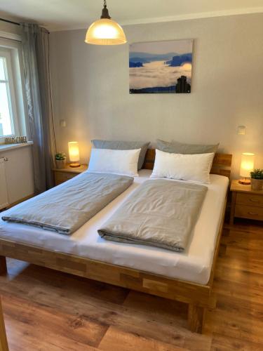 a large bed in a bedroom with two lamps at Sandstein-Ferien, Kamin, Fewo "Wanderfalke", zentral & ruhig, Terrasse, Sächs Schweiz in Königstein an der Elbe