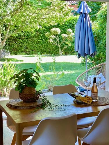 - une table avec un parapluie bleu et une bouteille de vin dans l'établissement Appartement neuf et au calme proche Avignon, à Althen-des-Paluds