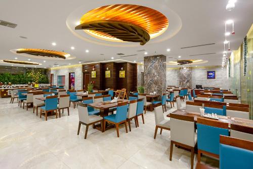 a restaurant with wooden tables and blue chairs at Aria Grand Hotel & Spa in Da Nang