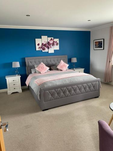 a bedroom with a large bed with a blue wall at Lochview Chalet in Eyre