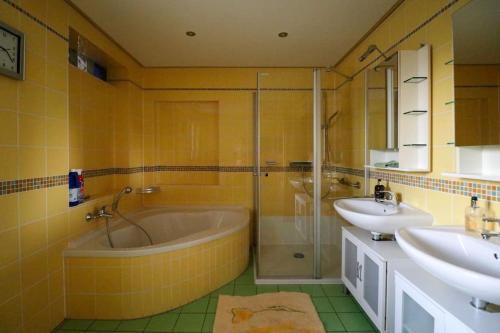 een badkamer met een bad, 2 wastafels en een douche bij Großes Haus, Sauna, Garten, top Wohnlage Inklusive Saarlandcard in Rehlingen-Siersburg