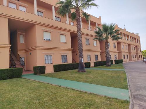 a large building with palm trees in front of it at la hacienda in Islantilla