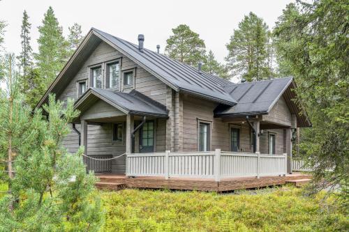 a wooden house with a porch in the woods at Rukan Lumikonpesä in Ruka