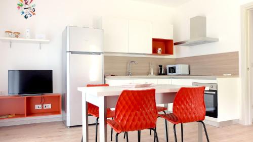 a kitchen with a white table and red chairs at Casa di Elisa in Gardone Riviera