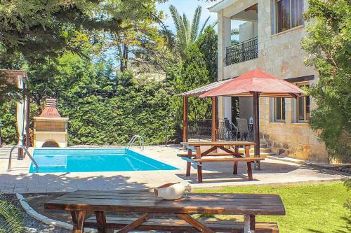 einen Pool mit einem Picknicktisch und einem Sonnenschirm in der Unterkunft Villa Agathi in Argaka