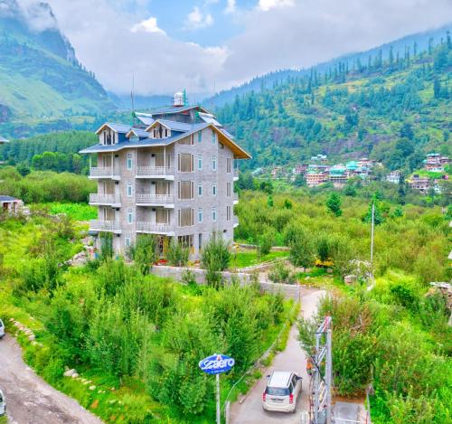 un bâtiment sur une colline avec des voitures garées devant lui dans l'établissement La Aero Resort Home in Snow Mountains, à Manali