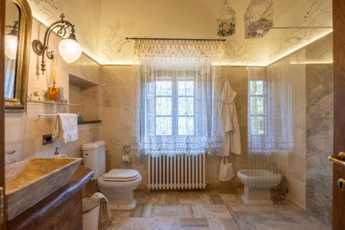 a bathroom with a toilet and a sink and a window at Podere la Casina Country Chic in Rigomagno