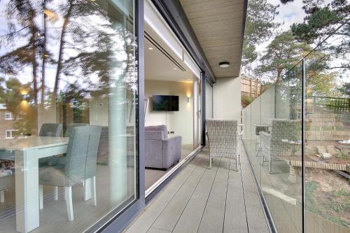a balcony with glass doors and a table and chairs at Luxury 2 bed 2 bath Apartment in Canford Cliffs