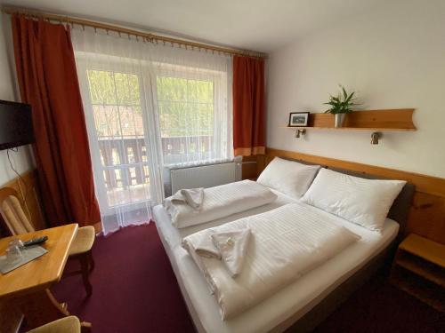 a bedroom with a white bed and a window at Hotel U STUDÁNKY in Jablunkov