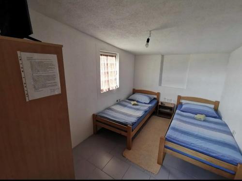 2 Betten in einem kleinen Zimmer mit Fenster in der Unterkunft Gostionica Kod Krlje in Nova Topola