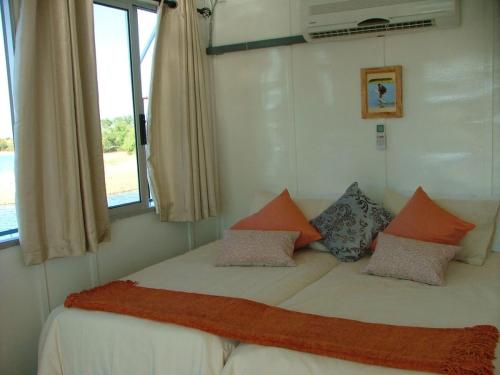 Houseboat with aircon and splash pool - 2128 في Kariba: غرفة نوم بسرير ومخدات ونافذة