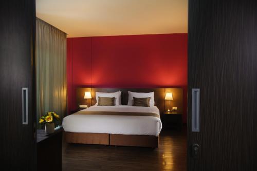 a bedroom with a large bed with a red wall at Coco View Hotel in Samut Songkhram
