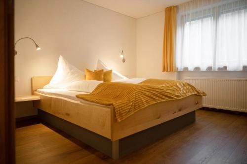 een slaapkamer met een bed met witte lakens en gele kussens bij Rosis Ferienwohnung in Vandans